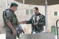 An Israeli soldier checks the Israeli-issued ID card of a Palestinian at one of the many checkpoints within the city of Hebron.   (© Photo: Rich Wiles/BADIL, 2012)